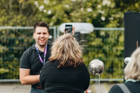 Expérience d’électricité statique : les cheveux d’une visiteuse se dressent, sous l’œil amusé d’un animateur.