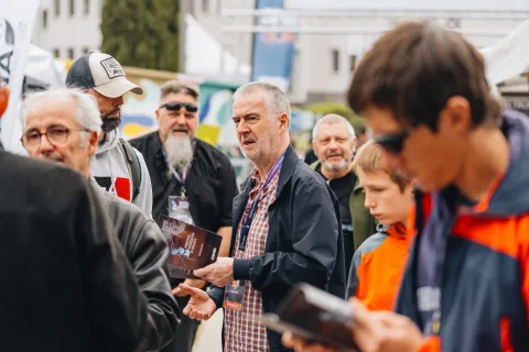 Visiteurs et intervenants qui discutent en extérieur, programme à la main.