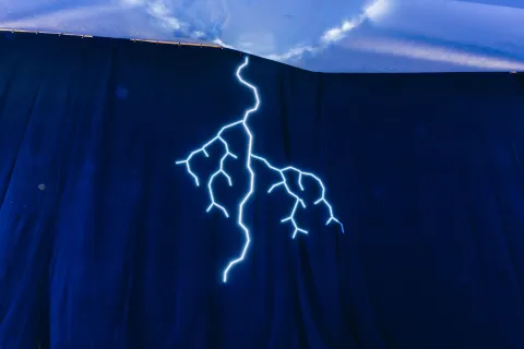 Éclair lumineux dessiné sur un rideau bleu nuit.