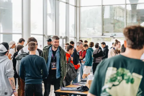 Foule de visiteurs dans le hall vitré, autour de la table d’accueil.