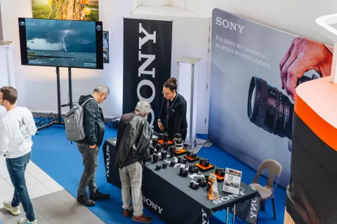 Stand Sony : visiteurs devant les appareils photo en démonstration.