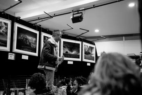 Matinée des scolaires : un intervenant présente l’exposition de photographies d’orages en noir et blanc à des élèves.