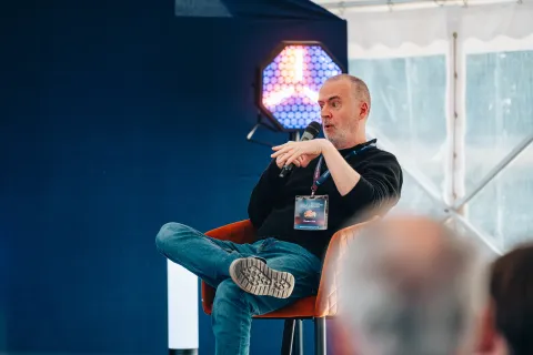 Intervenant assis dans un fauteuil, micro en main, pendant une discussion.