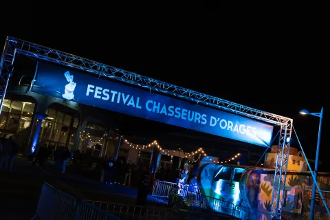 L’arche « Festival Chasseurs d’Orages » illuminée de bleu à la tombée de la nuit.