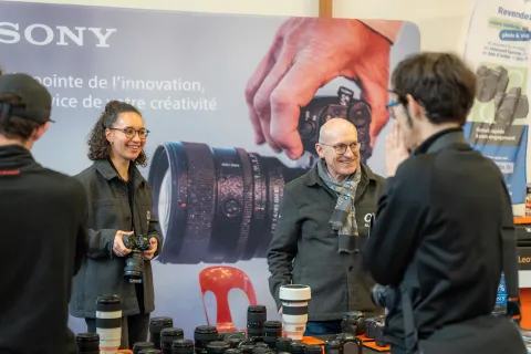 Stand Sony : deux visiteurs essaient des appareils photo, sourire aux lèvres.