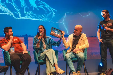 Table ronde sur scène : quatre intervenants, l’une brandit un diplôme, devant la projection d’un orage.