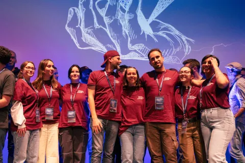 L’équipe des bénévoles en t-shirts bordeaux réunie sur scène pour la clôture.